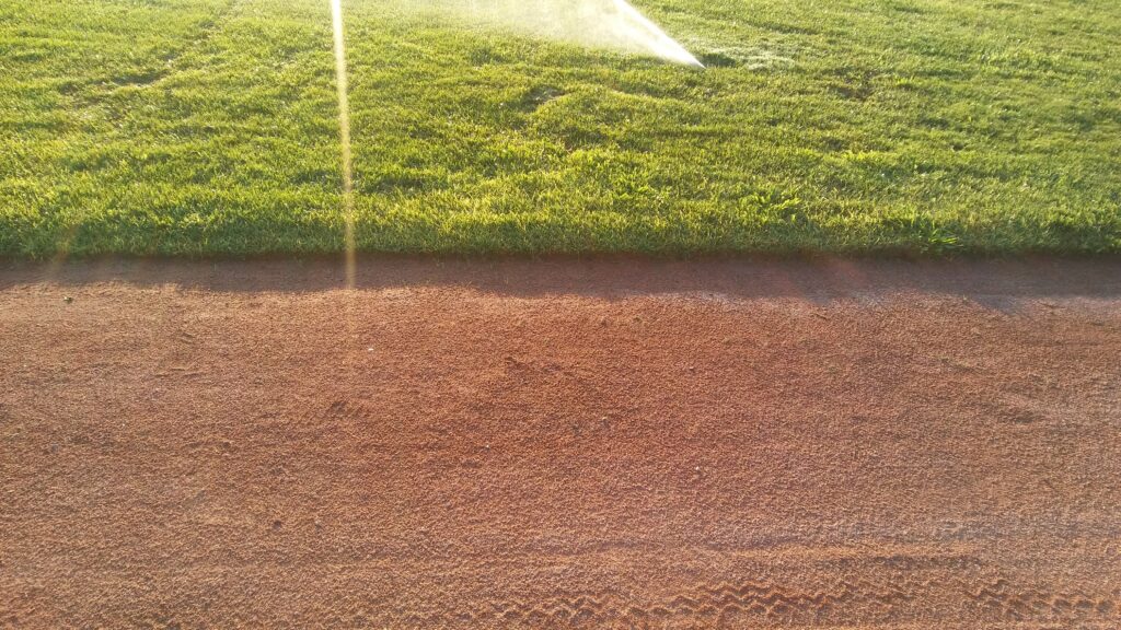 Irrigating green lawn on baseball field